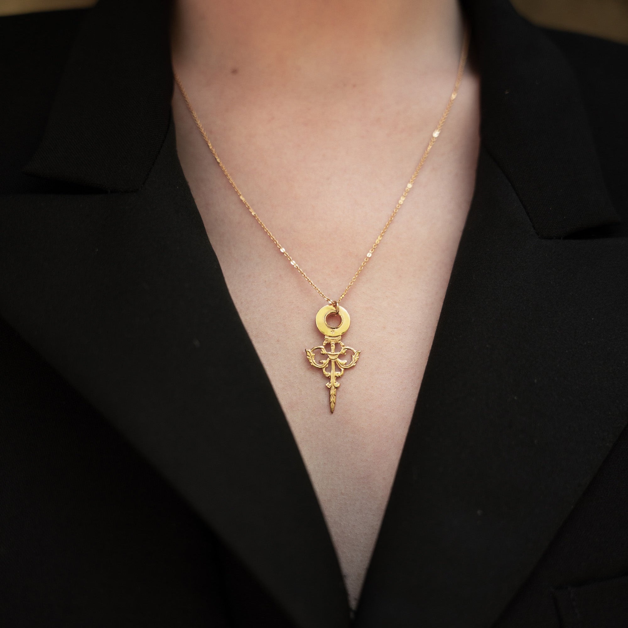 photo close up du collier doré minuit portée par une modèle à la veste noire