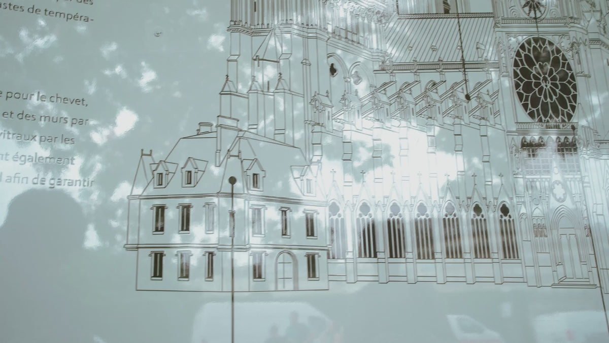 La vidéo montre le dessin explicatif de la cathédrale Notre-Dame, situé juste à coté de celle-ci. Une main apparait et vient montrer l'emplacement de l'horloge Collin.